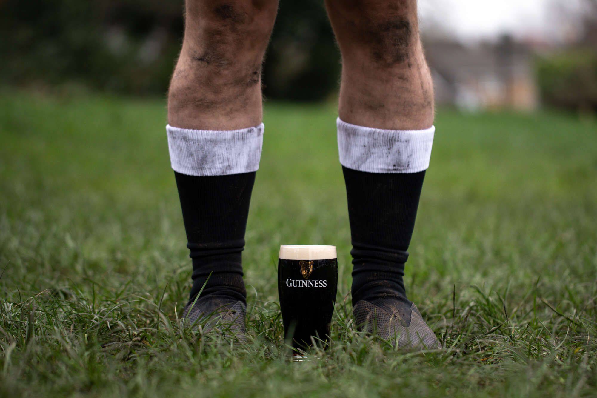 A rugby player stands in front of a pint of Guinness